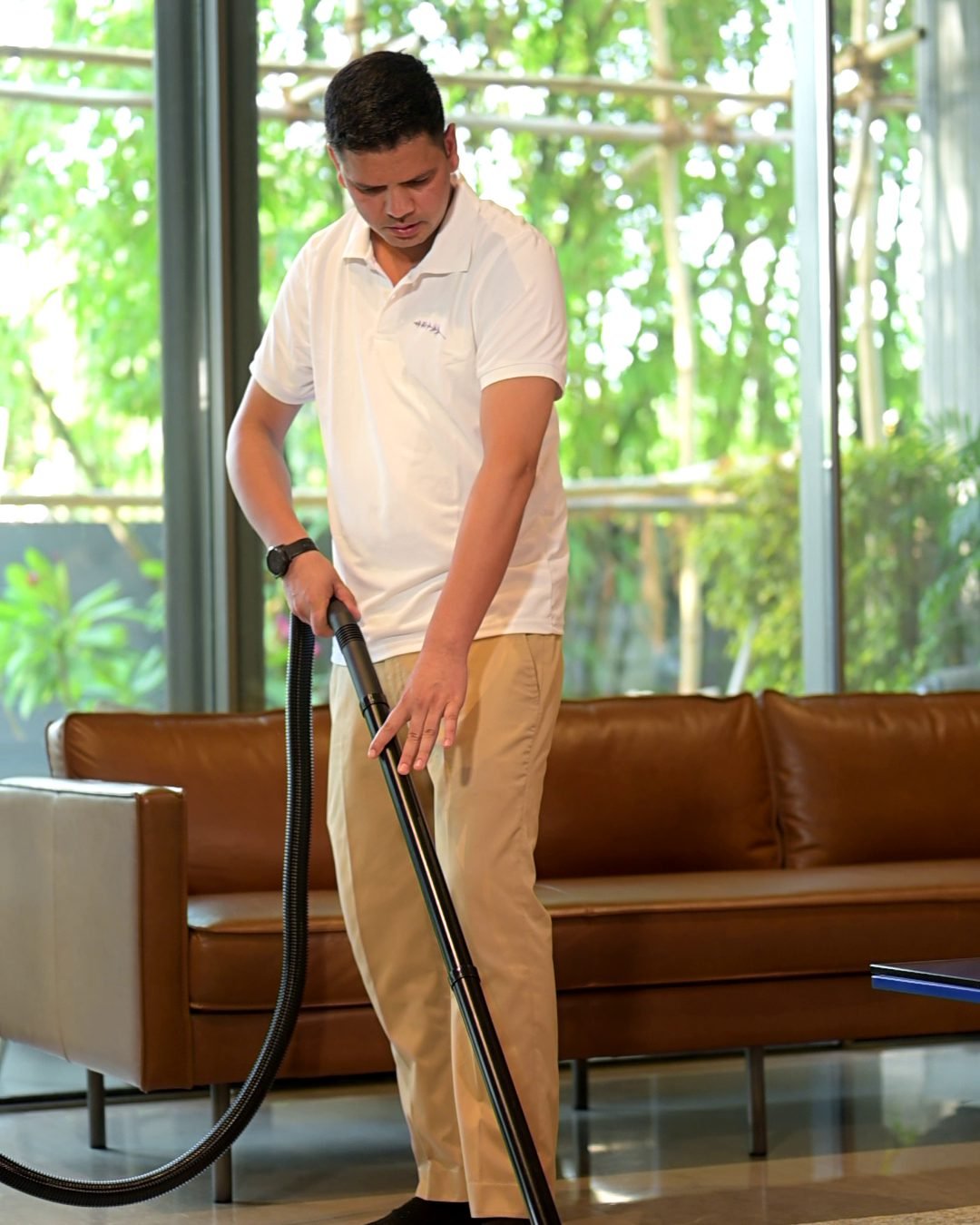 A Lavender housekeeper vacuuming a living-room carpet