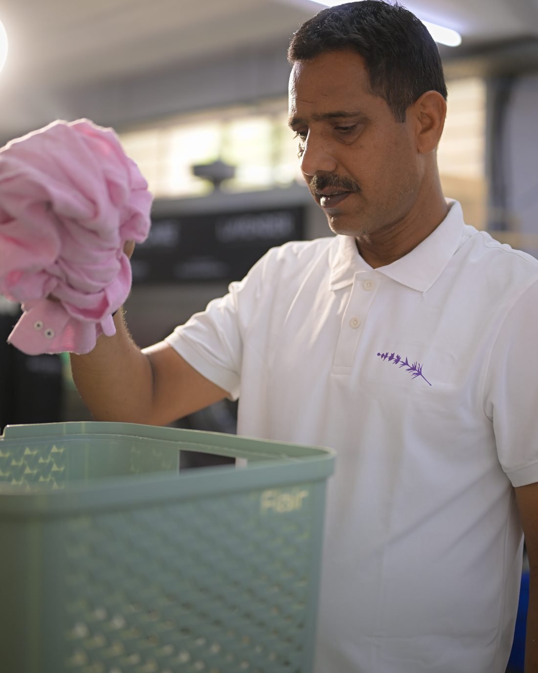 Lavender staff carrying a basket of collected laundry