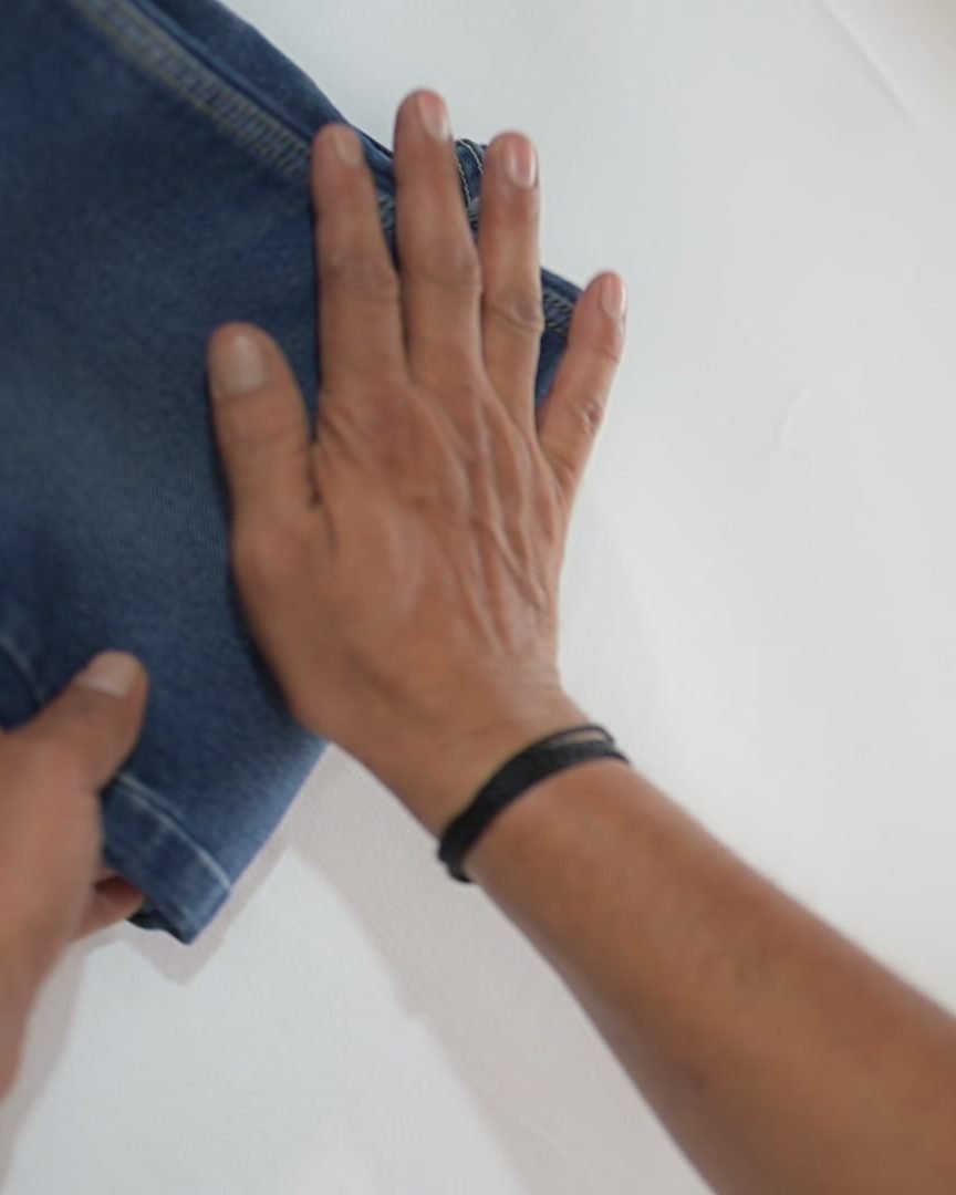 A Lavender technician folding freshly laundered denim